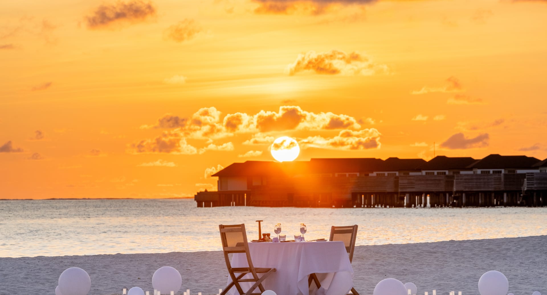 Romantic beachfront dinner at luxury Maldives resort with sunset view and overwater villas at Adrift - Avani+ Fares Maldives