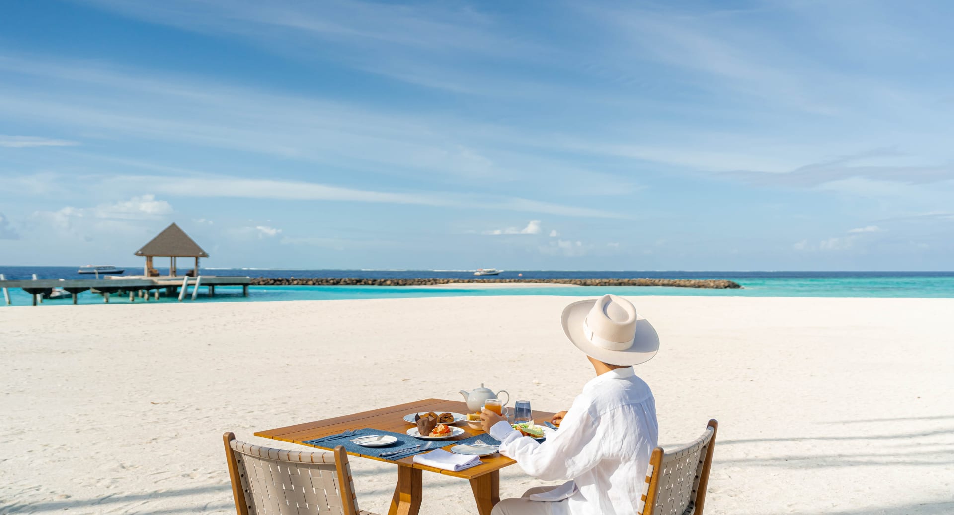 Guest enjoying private dining on white sand beach at Avani+ Fares Maldives resort