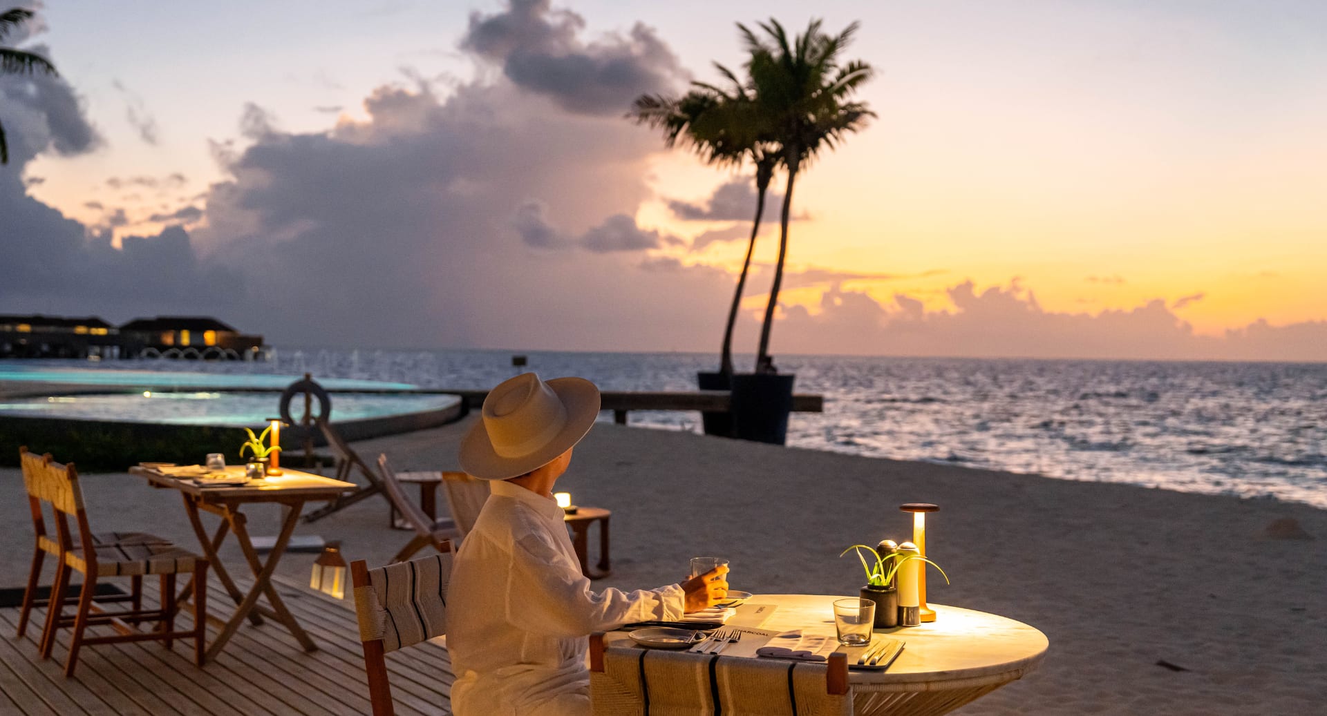 Guest enjoying romantic beachfront dinner at Avani+ Fares Maldives during sunset