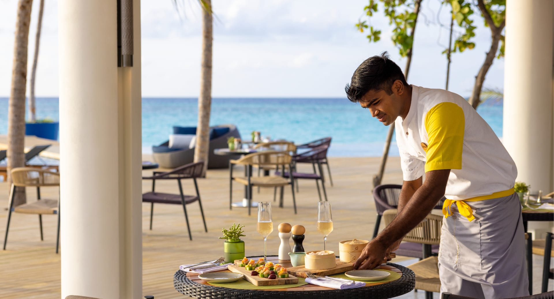 Resort staff serving beachfront dining at Avani+ Fares Maldives with ocean views