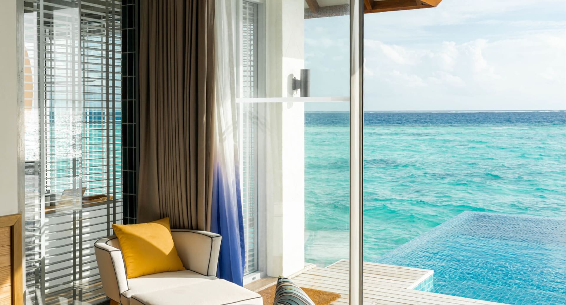 Oceanfront villa seating area with infinity pool at Avani+ Fares Maldives Resort.