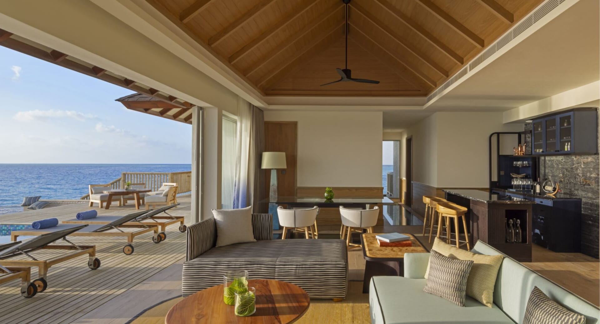 Spacious oceanfront villa living room with dining area and open terrace at Avani+ Fares Maldives