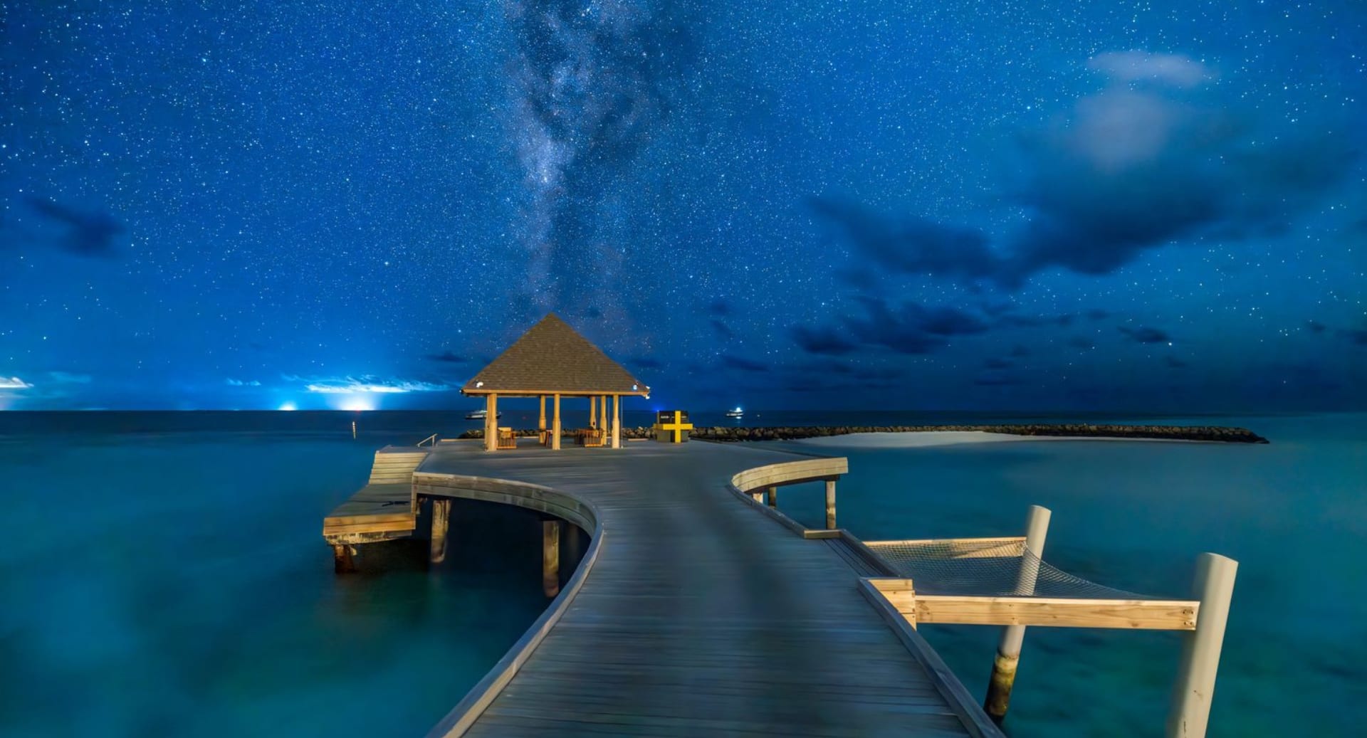 Starry night sky over arrival jetty at Avani+ Fares Maldives resort