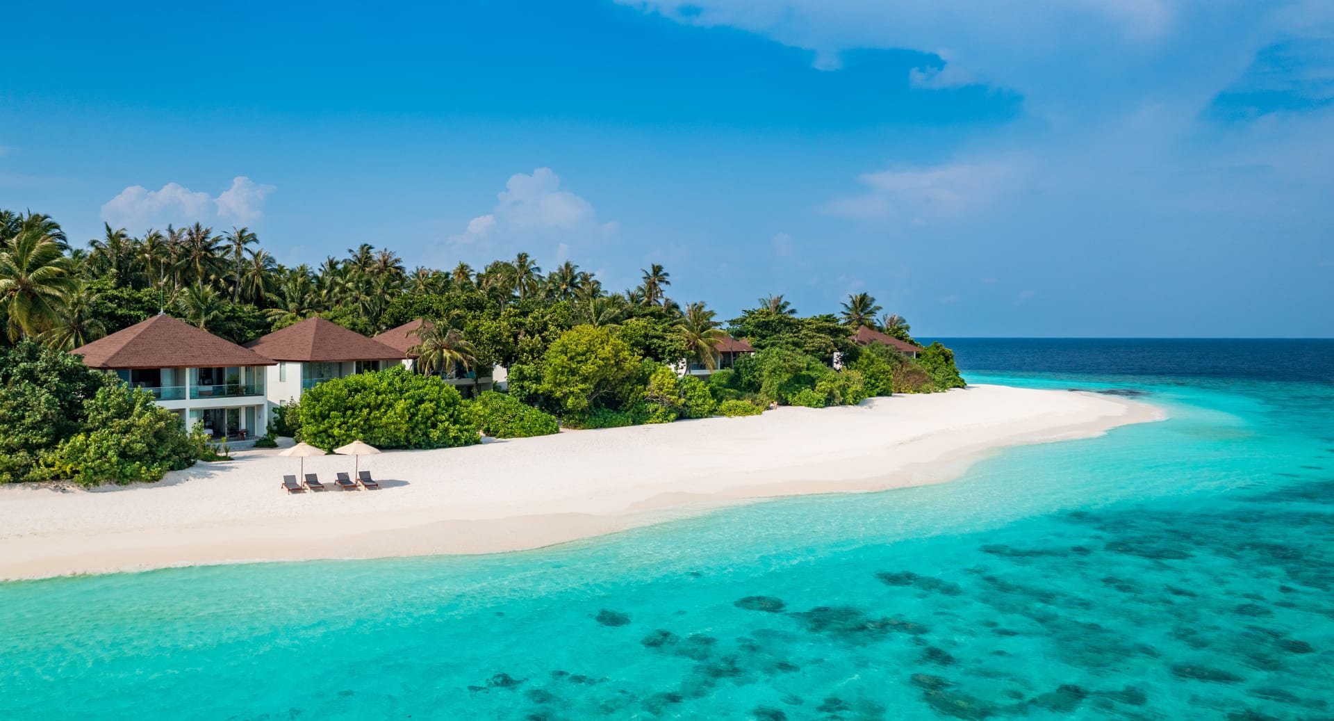 Oceanfront retreat surrounded by tropical greenery and crystal-clear lagoon at Avani+ Fares Maldives island resort