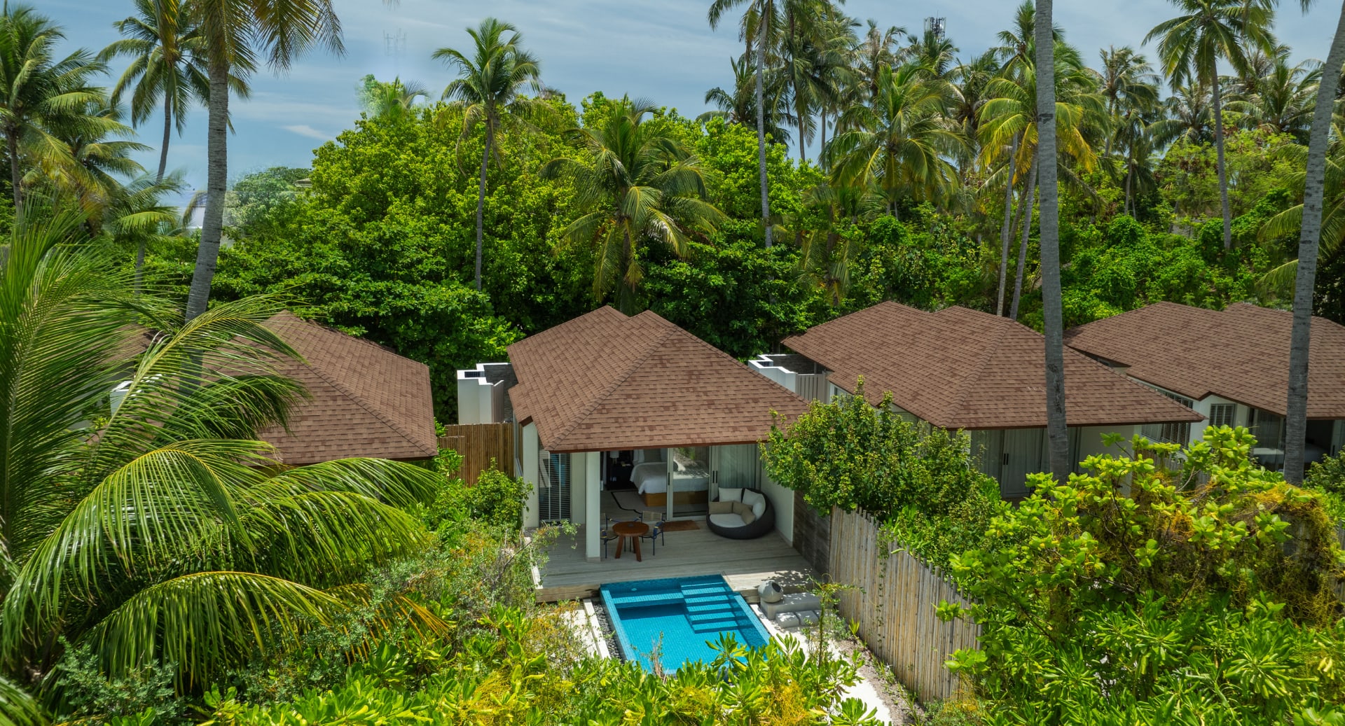 Private pool villas surrounded by tropical palm trees at Avani+ Fares Maldives Resort