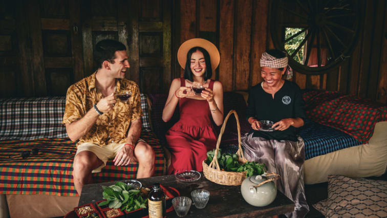 Unn Sophary enjoying beverages and smiling with a man and a woman, capturing a warm, friendly gathering at Herbal Kulen.