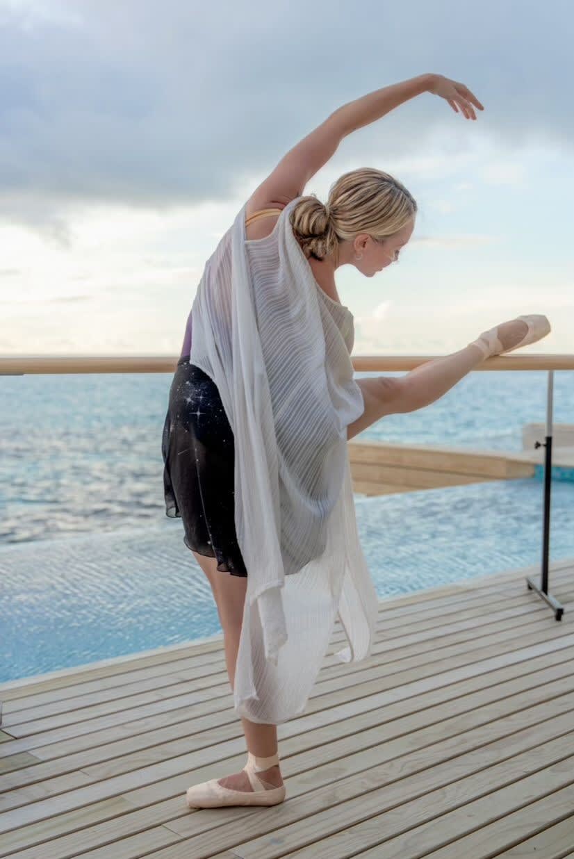 Karis Scarlette draped in fabric, striking a ballet pose facing the ocean at Avani+ Fares Maldives Resort.