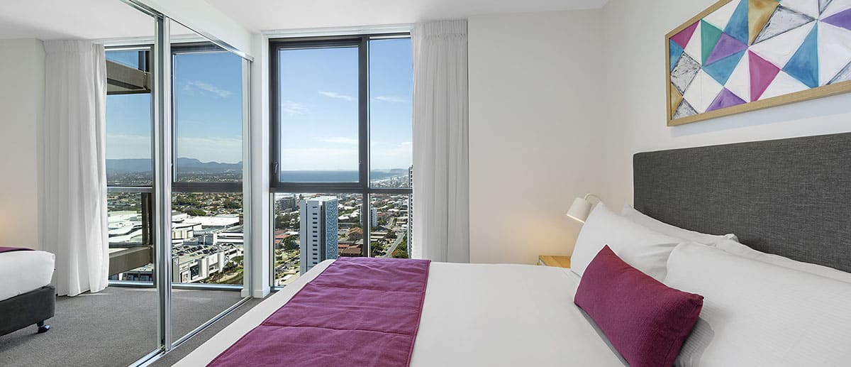 comfy queen-sized bed with city view at one bedroom ocean suite AVANI Broadbeach Gold Coast Hotels