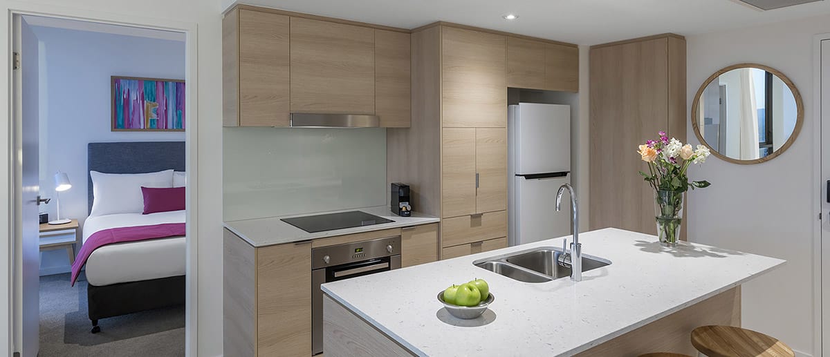 Spacious and well-appointed kitchen with fridge, oven, stove top and dining table provided at the two bedroom ocean suite AVANI Broadbeach Gold Coast Hotels