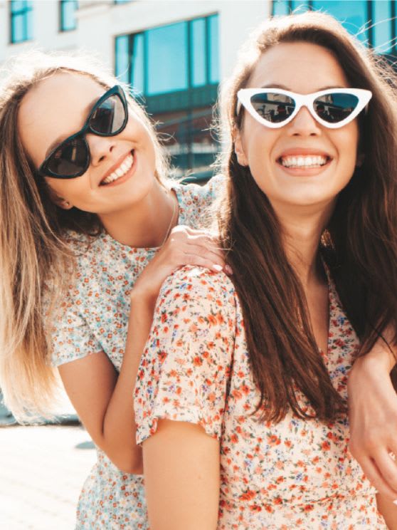 Two young girls wearing sunglasses and smiling