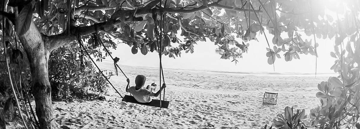 A little boy playing with a swing at the beach